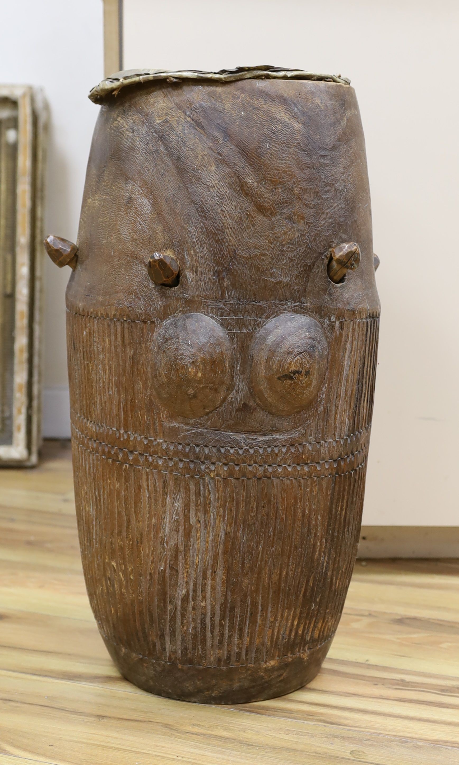 A 19th/20th century Ashanti breasted drum, 61 cms high.